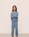 Model is wearing Kid's French Terry Sweatshirt and Jogger Set in Faded Denim