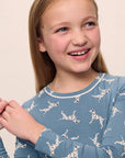 Model is wearing Kids Printed TENCEL™ Modal Unisex Long PJ Set in Dalmatian Faded Denim/Ivory